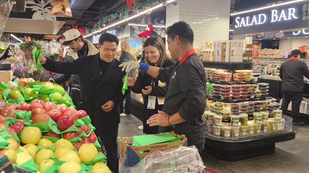 A produce department employee at Morton Williams on Broadway in New York, NY, showed Manhattan tour participants the art of folding apple papers, which are used to wrap each apple in a bulk display.