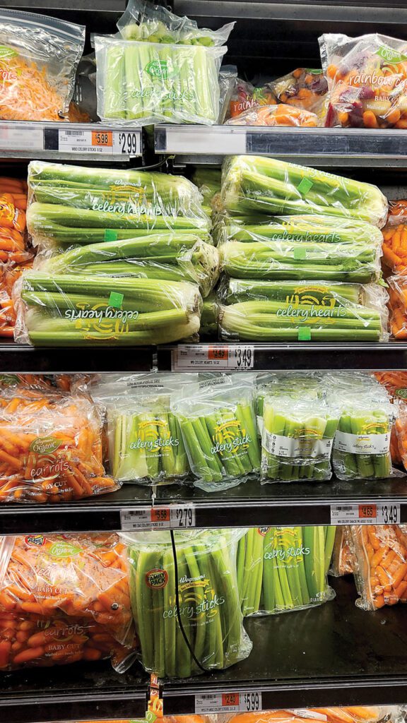 Celery is often displayed in refrigerated cases in the produce department near complementary vegetables like carrots.