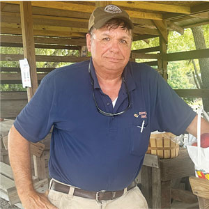 Tommy Chappell, owner of Chappell Farms standing next to bags and buckets of fresh peaches.