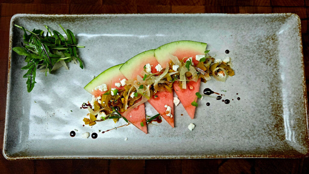 Chef Christopher Delissio created this Watermelon with Tangerine Chili Olives. In 2025, Delissio was one of 12 winners in the Kitchen Collaborative culinary menu ideation competition with another entry, Togarashi-Crusted Watermelon with Spicy Hoisin-Honey Chili Crunch Sauce and Pickled Watermelon Rind. The National Watermelon Promotion Board sponsored him in the competition.