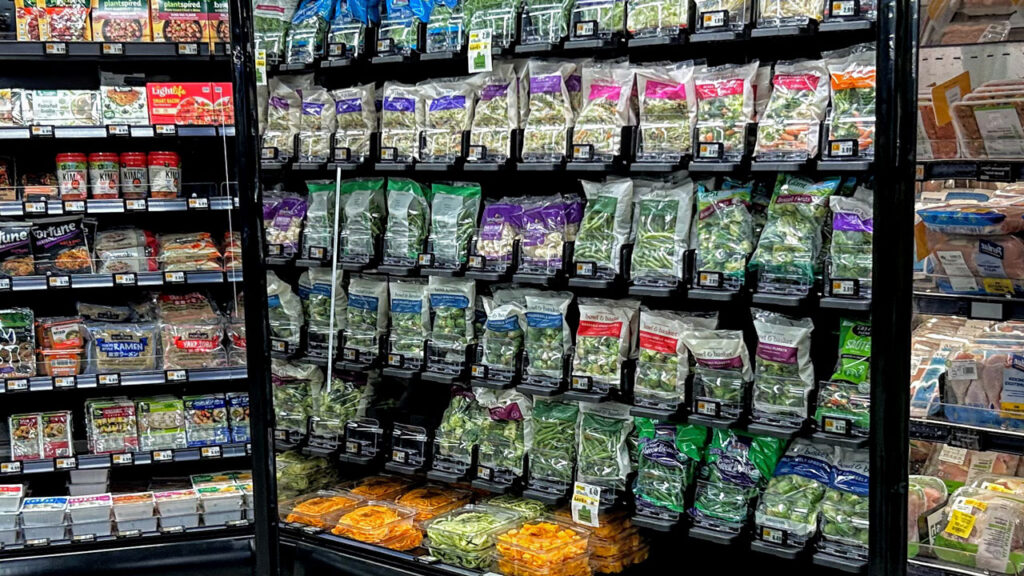 A single cold case section on the back wall features bagged salads with fresh-cut vegetables, along with packaged veggies, including those under Wakefern’s Bowl & Basket private label.